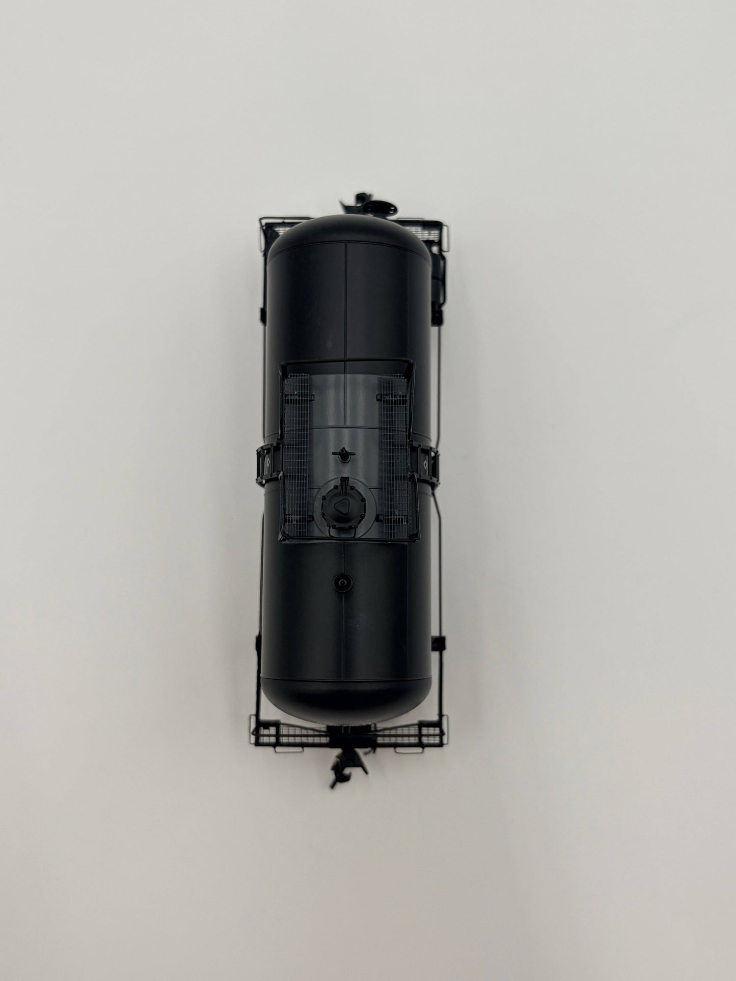 Black cylindrical tank with a grid-like structure on a light gray background